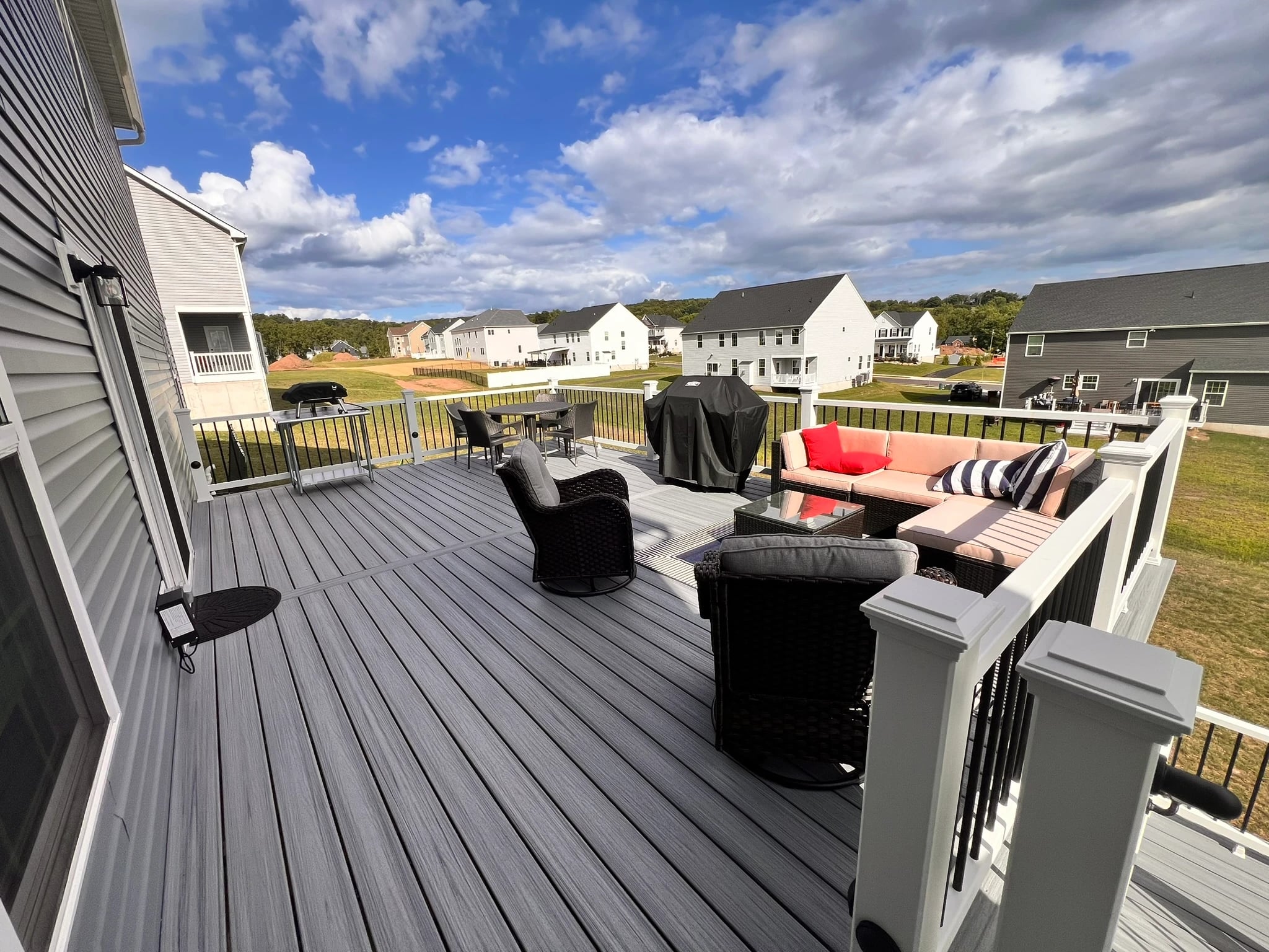 A finished VM Power deck furnished with outdoor seating and a grill beneath an open sky