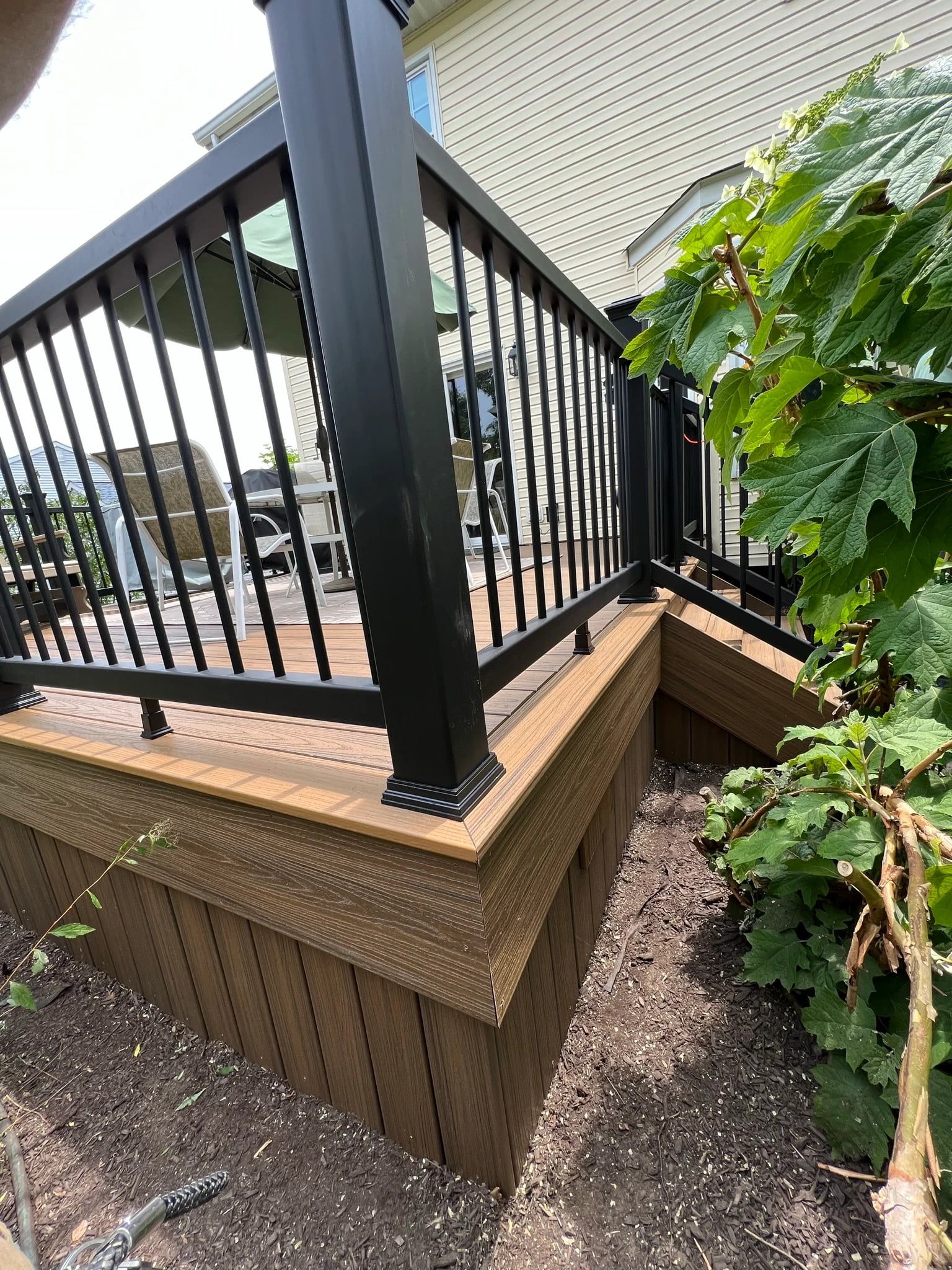 Close view of finished deck boards, black railing and garden planting