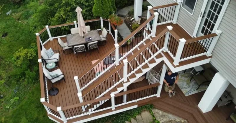 Two connected deck levels with white railing, stairs and outdoor seating